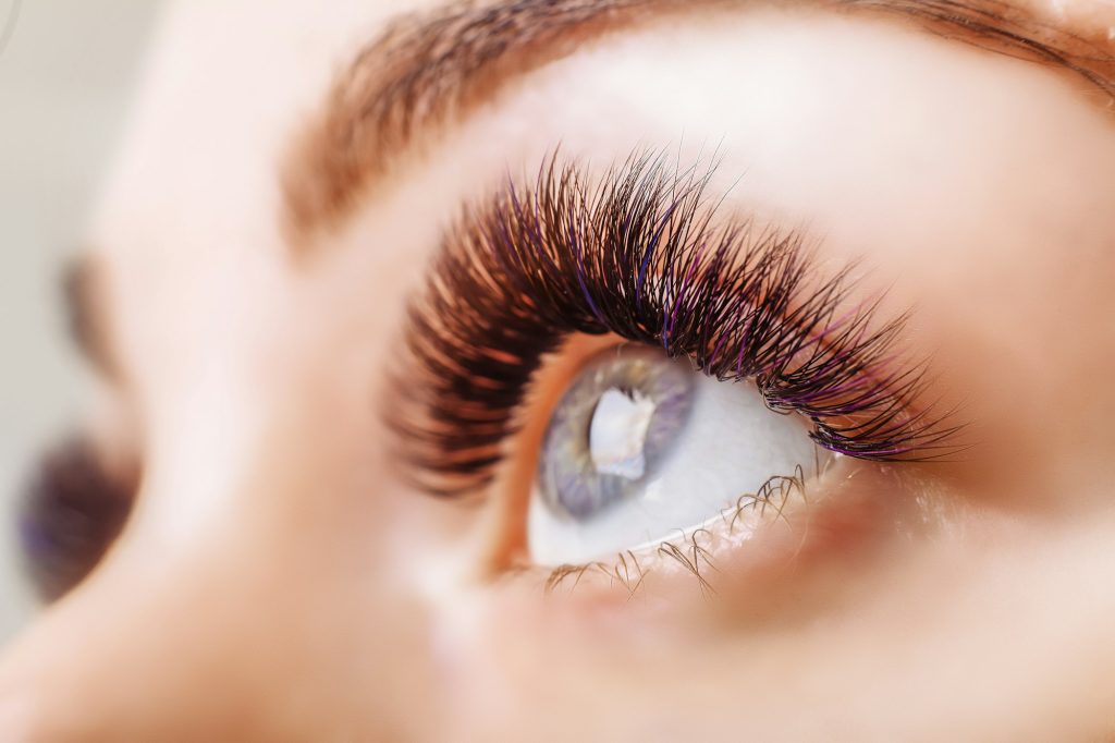 Eyelash Extension Procedure. Woman Eye with Long Eyelashes. Close up, selective focus